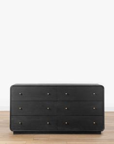 a black dresser sitting on top of a hard wood floor next to a white wall