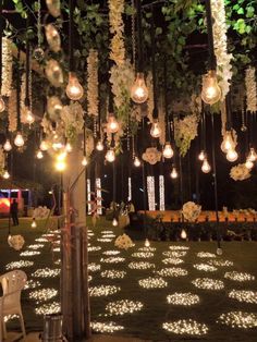 an outdoor event with lights and flowers hanging from the ceiling