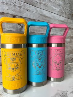 three different colored insulated water bottles sitting on top of a counter