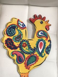 a painted chicken sitting on top of a white cushion