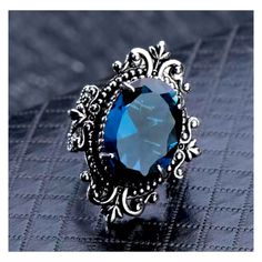 an oval blue stone surrounded by filigrees sits on top of a black surface