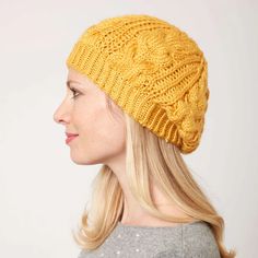 a woman with blonde hair wearing a yellow knitted hat and looking off to the side