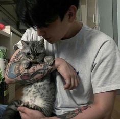 a man holding a cat in his arms with tattoos on it's arms and chest