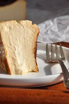 a piece of cheesecake on a white plate next to a fork and napkin with silverware