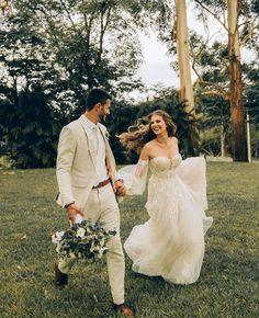 a bride and groom walking through the grass