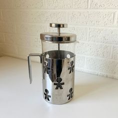 a stainless steel french press coffee maker on a white counter