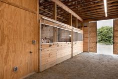 the inside of a horse barn with wooden walls and doors that are open to let in natural light