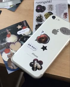 an iphone case with stickers on it sitting next to a magazine and some other items