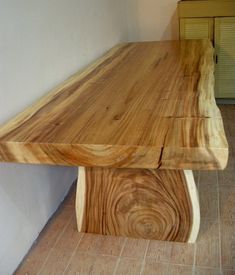 a wooden table sitting on top of a tile floor next to a cabinet and door