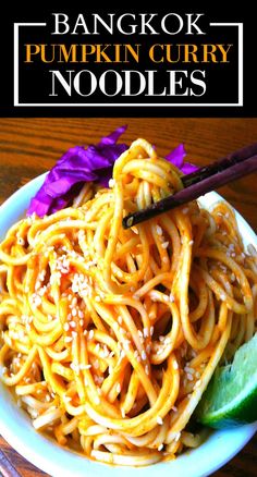 a white plate topped with noodles next to chopsticks on top of a wooden table