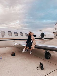 two people sitting on the nose of an airplane