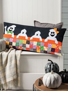 a halloween themed pillow on a bench with pumpkins and other decorations in the background