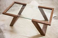 a glass and wood coffee table on top of a piece of paper that is laying on the floor