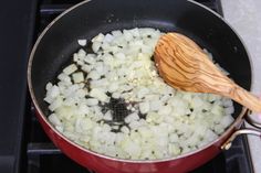 a wooden spoon stirring onions in a pot on the stove top with a black burner