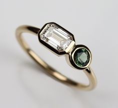 an emerald and diamond engagement ring on a white background with the stone in the middle