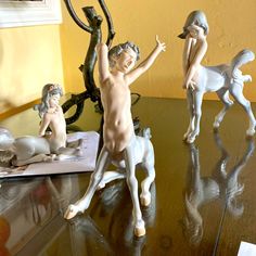 three little figurines sitting on top of a wooden table next to a mirror