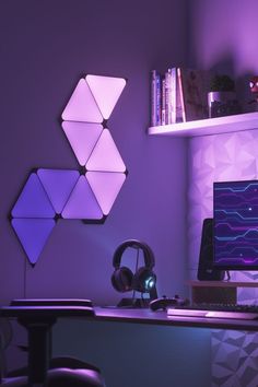 a computer desk with headphones on top of it in front of a purple wall