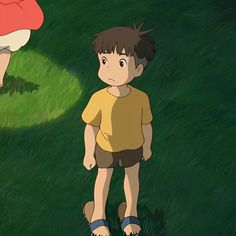 a young boy standing in the grass next to an older man