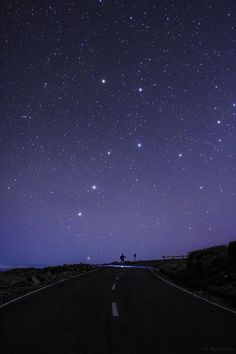 the night sky is filled with stars above a road