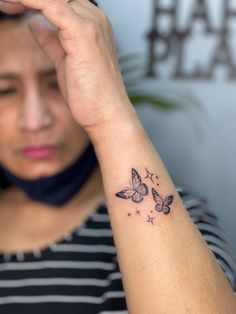 a woman with a butterfly tattoo on her left arm and the other hand behind her head