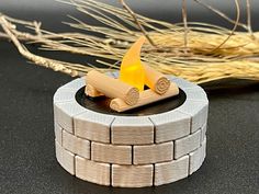 a small fire pit made out of wood and bricks with a yellow flame on top