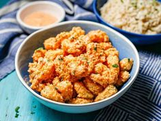 a bowl filled with fried tater tots next to two bowls of rice