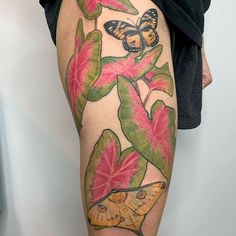 a woman's leg with colorful tattoos and flowers on her thigh, which has a butterfly sitting on the flower