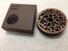 a wooden box with an intricate design on the lid next to it's packaging