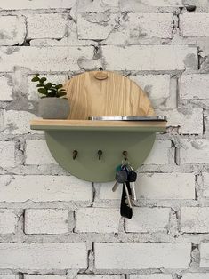 a wooden cutting board mounted to the side of a brick wall with keys hanging from it