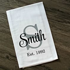 a white dish towel with the word smith est 1909 on it sitting on top of a wooden table