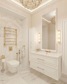 a white bathroom with gold fixtures and marble counter tops, along with a chandelier