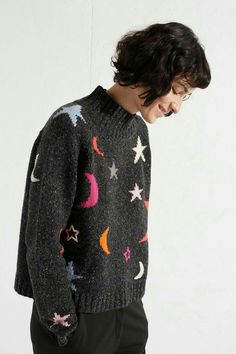 a man wearing a black sweater with stars and moon designs