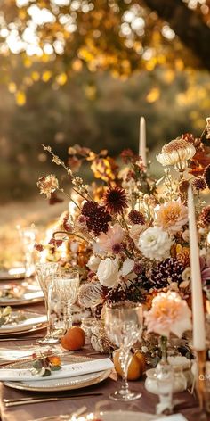 a table set with flowers and candles for an outdoor dinner party in the fall or winter