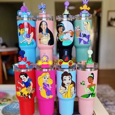 there are many disney princess tumblers on the table