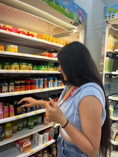 a woman is looking at canned food in a store she's pointing to the shelf