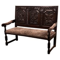 a wooden bench with ornate carvings on it's back and seat cushion, against a white background