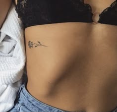 a woman's stomach with a small tattoo on her left side ribcage