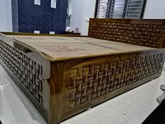 a large wooden bed frame sitting on top of a white floor next to a blue wall