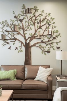 a living room with a brown couch and a tree on the wall above it that has birds flying around