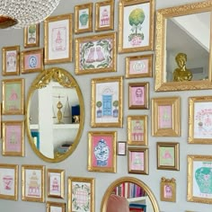 there are many framed pictures on the wall with gold trimmings and pink accents