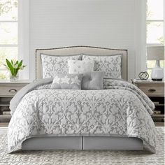 the comforter is made up with white and gray bedding, along with pillows