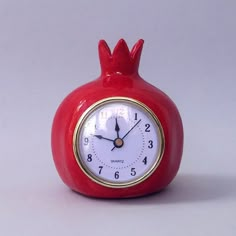 a red pomegranate clock sitting on top of a table