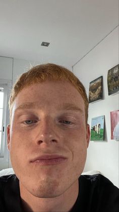 a man is taking a selfie in front of a wall with pictures on it