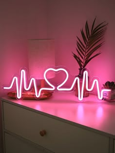 a neon sign that says i love you next to a potted plant on a dresser