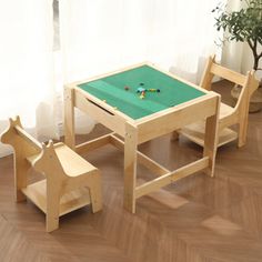 a child's wooden table and chair set in front of a window