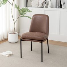 a brown chair sitting on top of a carpeted floor next to a potted plant