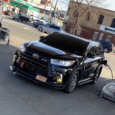 a black car is plugged in to an electric charger on the side of the road