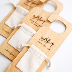 three wooden bottle openers with white linen bags tied around the top one is open and two are closed