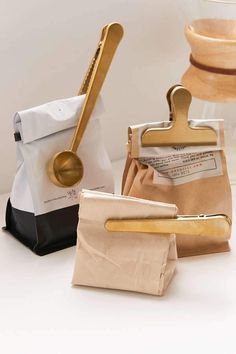 three wooden utensils and two paper bags on a white counter with gold handles