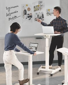 two people standing in front of a whiteboard with laptops on it and one person pointing at the screen